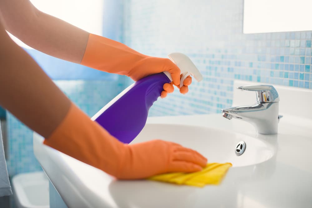 A person cleaning their bathroom using traditional cleaning products